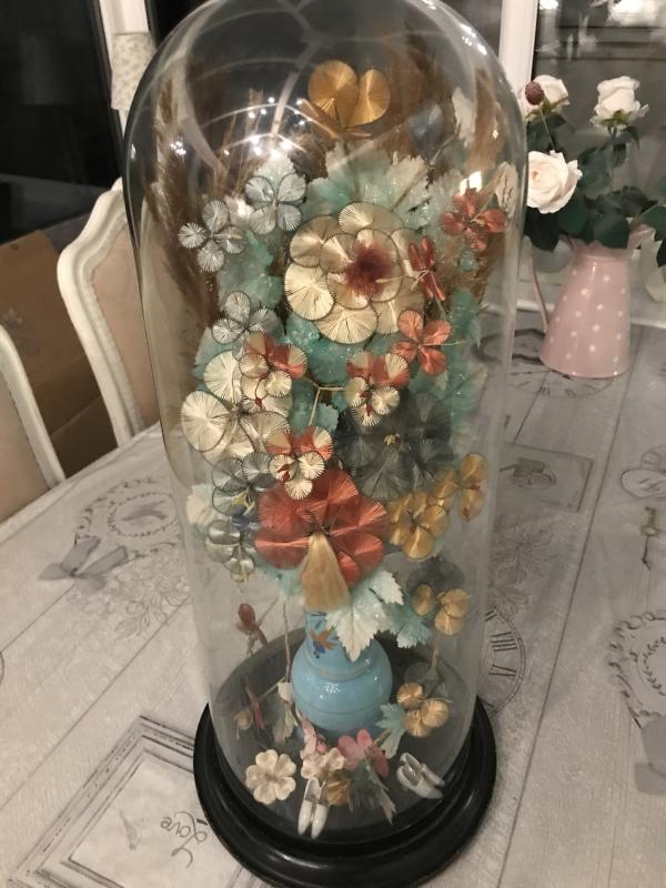 Tall Victorian glass dome containing silk flowers.